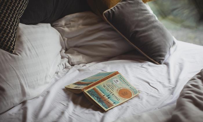 Close up of an unmade bed with an open book on it.